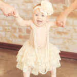 Baby-Girl-Standing-Holding-Mom-And-Dad-Hands-Lace-Tutu-Headband-Pearls-Best-Photography-Studio-Los-Angeles