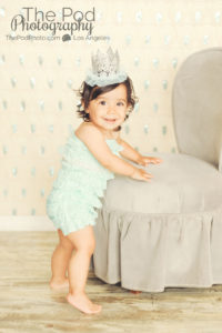 Best-First-Birthday-Cake-Smash-Photographer-Los-Angeles-Portrait-Studio-Teal-Romper-Sequins-Sparkle-Princess-Crown-Silver-Standing-Cute-Girly-Style