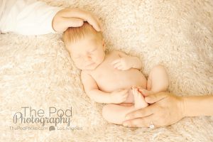 newborn baby on beige fur fabric with parents holding him photo