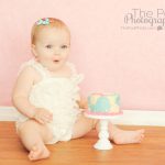 baby-smashing a pink and blue first birthday cake