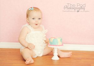 baby-smashing a pink and blue first birthday cake