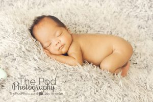 infant-snuggled-on-gray-fabric