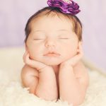 purple-newborn-baby-holding-her-head-in-her-hands
