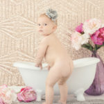 naked-baby-butt-standing-by-miniature-bathtub-with-flowers
