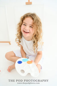 girl-smiling-holding-paint-palette-family-photo