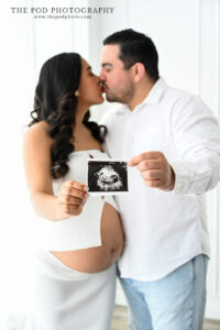 couple-kiss-holding-ultrasound-maternity-the-pod-photography